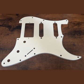 Stříbrný kovový pickguard pro elektrickou kytaru s výřezy pro tři snímače. Povrch je hladký a reflexní, bez viditelných značek, log nebo nápisů. Kous…