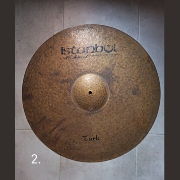 Kruhová mosazná činely s kladeným povrchem. V horní části je černý nápis „istanbul“ a pod ním menší text „Mehmet Handmade cymbals from Turkey“. Ve sp…