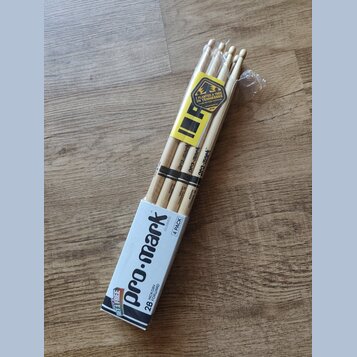 Balení čtyř dřevěných bubeneckých paliček v papírové krabici a plastovém obalu. Na krabici i na paličkách je nápis pro-mark, označení 2B HICKORY FORW…