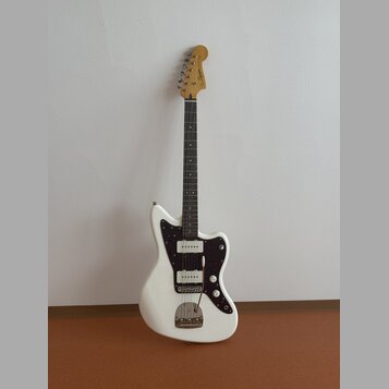 Bílá elektrická kytara s černým pickguardem a hnědým hmatníkem. Na hlavě je viditelné logo Squier. Nástroj má dva snímače, tři ovládací knoflíky a je…