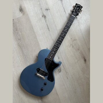 Modře lakovaná elektrická kytara s černým hmatníkem a černým pickguardem. Na hlavě je bílý nápis Gibson a pod ním nápis Les Paul. Nástroj má jeden sn…