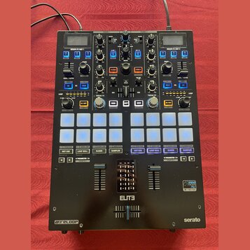 Černý DJ kontrolér s množstvím tlačítek, posuvníků a otočných knoflíků. Na přístroji jsou viditelné nápisy SERATO FX UNIT 1, SERATO FX UNIT 2, ELITE…