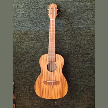 Dřevěný nástroj typu ukulele s přirozenou barvou a výraznou sletovanou strukturou dřeva. Na hlavě je viditelné logo ve tvaru stylizovaného písmena „C…