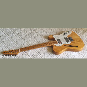 Elektrická kytara s přírodním dřevěným povrchem a hnědým hmatníkem. Na hlavě je nápis Greco, korpus má bílý perleťový pickguard a jeden f-otvor. Nást…