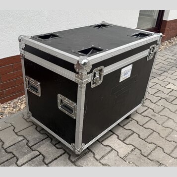 Černý transportní case s hliníkovými hranami a rohovými zpevněními. Na boku jsou dvě kovové rukojeti a na přední straně jeden zámek. Na pravém boku j…