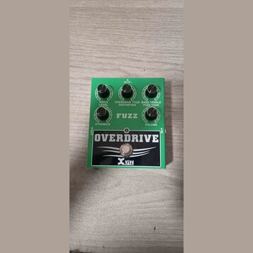 Zelený efekt pedál s černým panelem a bílými nápisy. Na černém panelu je velký nápis OVERDRIVE a logo Xvive. Na zelené části jsou čtyři černé ovládac…