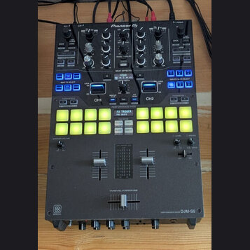 Černý DJ mixér značky Pioneer DJ, model PERFORMANCE MIXER DJM-S9. Zařízení obsahuje zahlreichetočítka, posuvníky a dvě řady podsvícených žlutých perf…