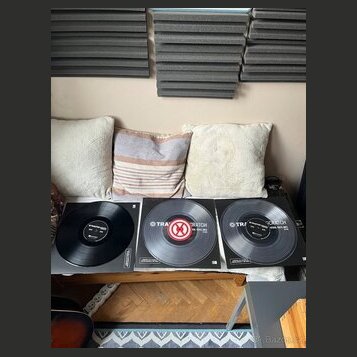 Tři vinylové desky v obalech položené na bílém podkladu. Na dvou z nich je viditelný nápis TRAX a SCRATCH, přičemž prostřední disk má červený středov…