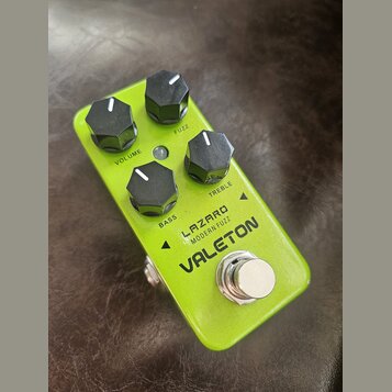 Zelený kytarový efekt pedál s kovovým šasi a čtyřmi černými ovládacími knoflíky. Na povrchu jsou nápisy VOLUME, FUZZ, BASS a TREBLE a výrazné logo VA…