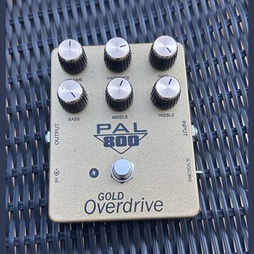Zlatý kytarový pedál s nápisem PAL 800 a GOLD Overdrive. Na horní straně se nachází šest otočných knoflíků s popisky VOLUME, PRESENCE, GAIN, BASS, MI…