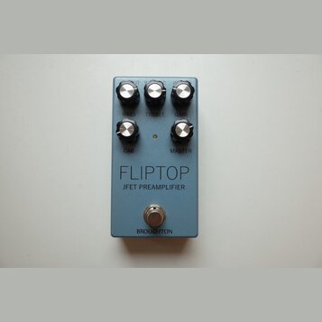 Modrý kytarový pedál s pěti černými ovládacími knoflíky. Na povrchu jsou nápisy BASS, TREBLE, GAIN, CAB a MASTER, dále velký text FLIPTOP a pod ním J…