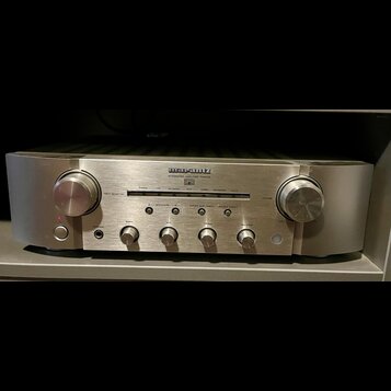 Stříbrný integrovaný zesilovač s kovovým povrchem. Na předním panelu je nápis marantz a pod ním INTEGRATED AMPLIFIER PM8005. Zařízení má dva velké ov…