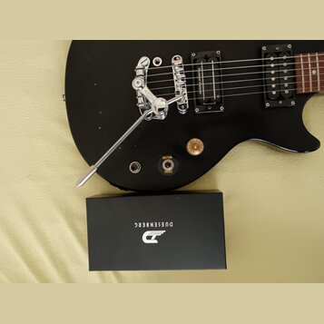 Černá elektrická kytara s chromovaným hardwarem a dvěma snímači. Na jednom ze snímačů je nápis Signature Humbucker. Pod snímači se nachází přepínač s…