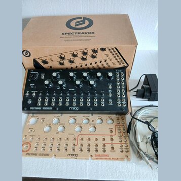 Na fotografii je semi-modulární procesor SPECTRAVOX od značky moog v doprovodu původního kartonového boxu a návodu. Zařízení je černé s bílými nápisy…