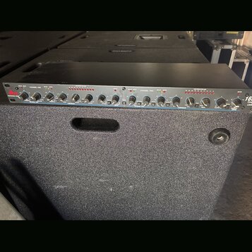 Černý rackový procesor s modrým předním panelem. Na levé straně je červené logo dbx a nápis PROFESSIONAL PROCESSOR. Zařízení obsahuje dva kanály s ov…