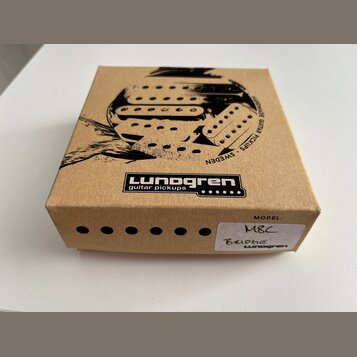 Hnědá kartonová krabice s černým potiskem. Na horní straně je logo „Lundgren guitar pickups“ a grafika znázornující snímače s nápisem „HANDMADE GUITA…
