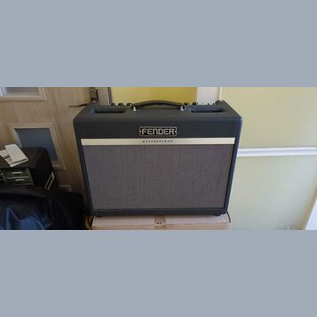 Kytarový kombo zesilovač značky Fender v tmavě šedém provedení s černou madlou. Na přední straně je stříbrný štítek s nápisy FENDER a BASSBREAKER™. P…