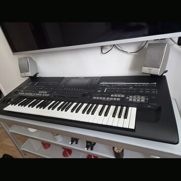 Černý digitální klavír s bílými a černými klávesami, umístěný na bílém stole. Na horním panelu jsou nápisy YAMAHA, 10th ANNIVERSARY a modelové označe…