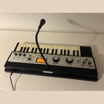 Černý syntetizátor s klaviaturou a ovládacím panelem. Na pravé straně je nápis KORG microKORG XL a na spodní hraně uprostřed logo KORG. Přístroj má v…