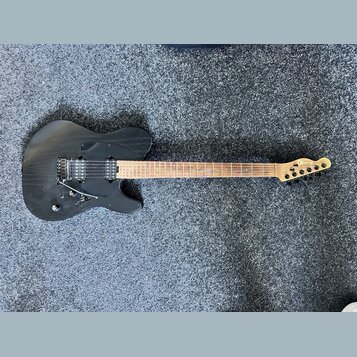 Černá elektrická kytara s hnědým hnedým hradlem a světlou barvou dřeva na hlavě. Na hlavě je viditelné logo OK. Kytara má dva humbuckery, tremolo mec…
