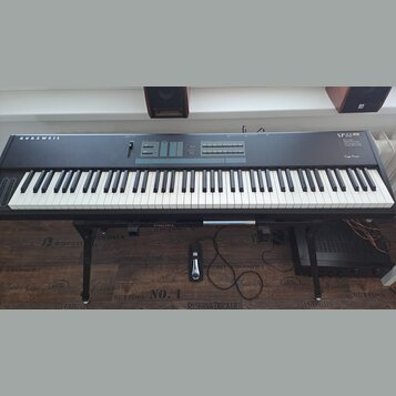 Černý digitální klavír na černém stojanu. Na levé straně je nápis KURZWEIL a vpravo označení SP88 Stage Piano. Horní panel obsahuje ovládací prvky, t…