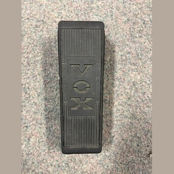 Černý sustain pedál s žebrovaným povrchem. Uprostřed je vyražen nápis VOX, který je v rámečku dopojen na text AMPLIFIER zleva a INSTRUMENT zprava. Po…