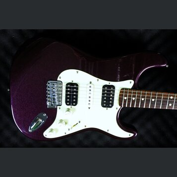 Elektrická kytara s tmavě fialovým metalizovaným povrchem těla a bílým pickguardem. Nástroj má konfiguraci snímačů humbucker-single-humbucker a tři b…