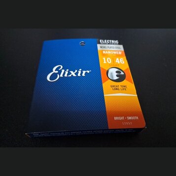 Fotografie znázorňuje balení strun pro elektrickou kytaru značky Elixir. Na modrém a oranžovém obalu jsou nápisy ELECTRIC GUITAR STRINGS, NICKEL PLAT…