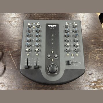 Šedý mixážní pult s nápisem MACKIE. U.420d. Zařízení obsahuje čtyři vstupní kanály s ovládacími knoflíky pro GAIN, EQ (HIGH, MID, LOW), AUX a LEVEL,…