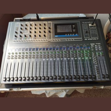 Míchací pult v transportním kufru s nápisy Soundcraft a Si IMPACT. Zařízení obsahuje digitální displej, početné posuvníky, knoflíky a tlačítka v šedé…
