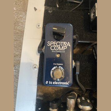 Modrý efekt pedál s nápisy SPECTRA COMP a BASS COMPRESSOR. Ve spodní části je uveden text true bypass a logo tc electronic. Zařízení vykazuje známky…