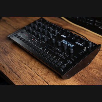 Černý digitální bubnový stroj s nápisy KORG a drumlogue HYBRID DRUM MACHINE. Zařízení obsahuje množství ovládacích knoflíků, malý displej s textem a…