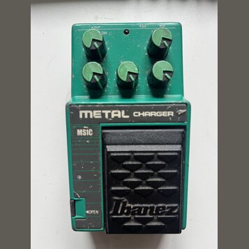 Zelený kytarový efekt s černým pedálem. Na horní části je nápis METAL CHARGER a na pedálu logo Ibanez. V levé části je viditelný nápis MSIC a v dolní…