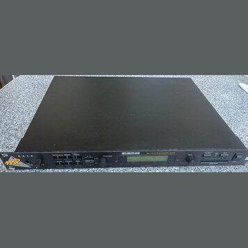 Černý rackový syntetizátor s nápisem ENSONIQ 64 Voice Expandable Synth. Na předním panelu jsou umístěny tlačítka, ovládací prvky a displej, v levém r…