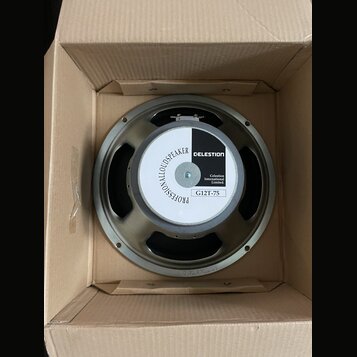Kruhový reproduktor v kartonové krabici. Na středovém krytí je bílo-černý štítek s nápisy PROFESSIONALLOUDSPEAKER, CELESTION, Celestion International…