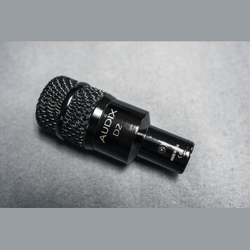 Černý dynamický mikrofon s kovovým tělem a mřížkovou hlavou. Na boku je bílý nápis AUDIX D2 a na spodní části text MADE IN USA CE. Povrch je v dobrém…