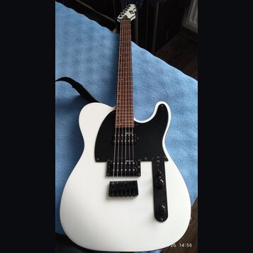 Bílá elektrická kytara s černým pickguardem a hnědým hmatníkem. Nástroj je vybaven dvěma snímači typu humbucker a černým mostem. Na hlavě krku je vid…