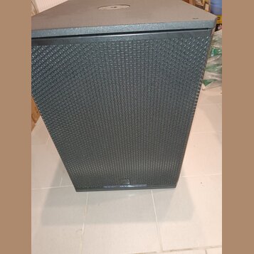 Černý subwoofer s kovovou perforovanou mřížkou přes celý přední panel. V dolní části je umístěn oválný štítek s nápisem tce a označením modelu SUB 18…