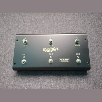 Černý obdélníkový spínací pedalboard s šesti kovovými přepínači. Na povrchu jsou bílé nápisy Rectifier., CH 1, CH 2, CH 3, MUTE, LOOP a SOLO. V dolní…