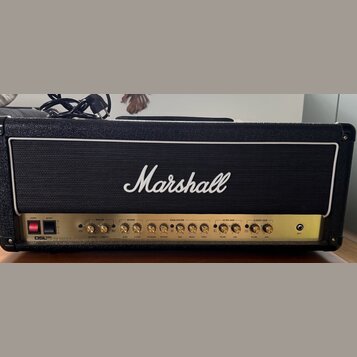 Kytarový zesilovač značky Marshall v černém texturovaném potahu s bílým lemováním mřížky. Zlatý ovládací panel obsahuje nápisy MASTER, REVERB, EQUALI…