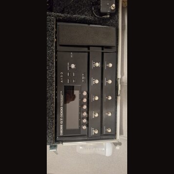 Černý kytarový procesor BOSS GT-1000 umístěný v transportním kufru. Na přístroji jsou viditelné nápisy GUITAR EFFECTS PROCESSOR, AIRD a ovládací prvk…