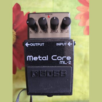 Kytarový efekt pedál značky BOSS, model Metal Core ML-2. Zařízení má černé kovové tělo s bílým nápisem a čtyři ovládací knoflíky na stříbrném horním…