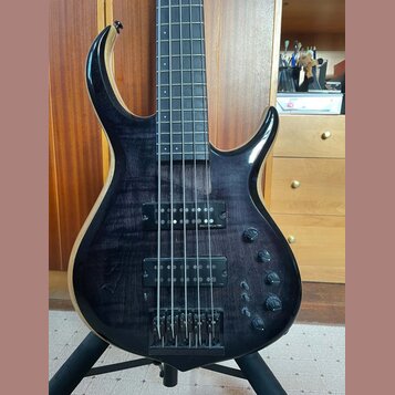 Tmavě hnědá basová kytara s výraznou strukturou dřeva a černým hardwarem. Na horním snímači je nápis "Sire Marcus Miller". Nástroj má dva snímače, čt…