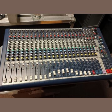 Modrý mixážní pult s kovovým panelem a множеstvem potenciometrů, přepínačů a posuvníků. V pravé dolní části je viditelné logo Soundcraft a označení m…