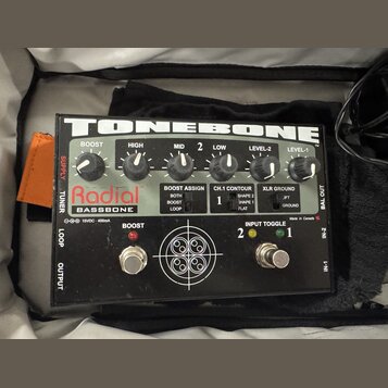Černý kytarový efekt Radial BASSBONE z řady TONEBONE. Na horní straně jsou umístěny šest otáčivých ovladačů s popisky BOOST, HIGH, MID, LOW, LEVEL-2…