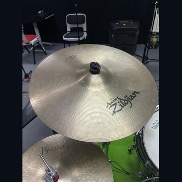 Fotografie zachycuje dva činely v mosazné barvě. Horní činel nese nápisy „Avid 6 Zildjian“ a v horní části menší text „THE GONG“. Spodní činel má náp…