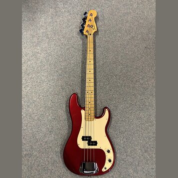 Třístrunná elektrická basová kytara s vínovým lakovaným tělem a krčkem z jasného dřeva. Na hlavě je viditelné logo Fender. Bílý pickguard obsahuje dv…