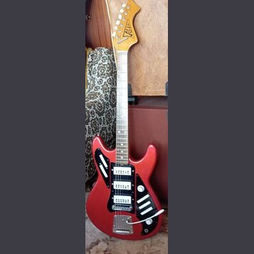 Červená elektrická kytara s matným povrchem a dřevěnou hmatníkovou palicí. Na hlavě je viditelné logo "Alt". Nástroj má dva bílé humbuckery, černý pi…