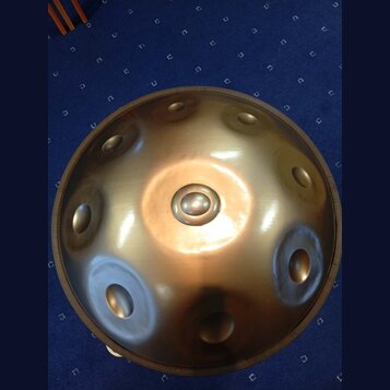 Kovový perkusní nástroj typu steel tongue drum v bronzové barvě. Nástroj má kulovitý tvar s několika vlisnými otvory rozmístěnými po povrchu. Povrch…