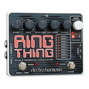 Efektový pedál s bílým rámem a černým povrchem. Na přední straně je velký červený nápis RING THING a pod ním text SINGLE SIDEBAND MODULATOR. V dolní…